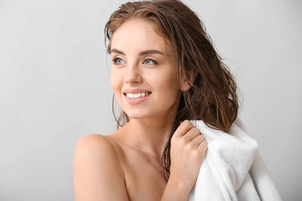 Hermosa mujer joven limpiando el cabello después de lavar contra el fondo gris —  Fotos de Stock