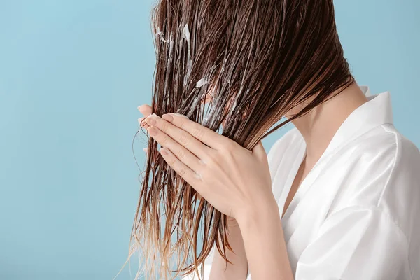 Güzel genç kadın renk arka plan karşı yıkadıktan sonra saçlarına mus uygulayarak — Stok fotoğraf