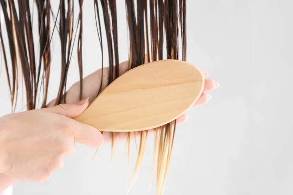 Mulher bonita escovando o cabelo após a lavagem em casa, close-up — Fotografia de Stock