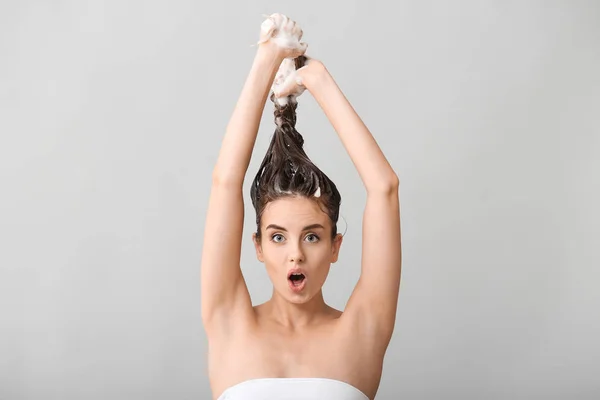 Lustige junge Frau beim Haarewaschen vor grauem Hintergrund — Stockfoto