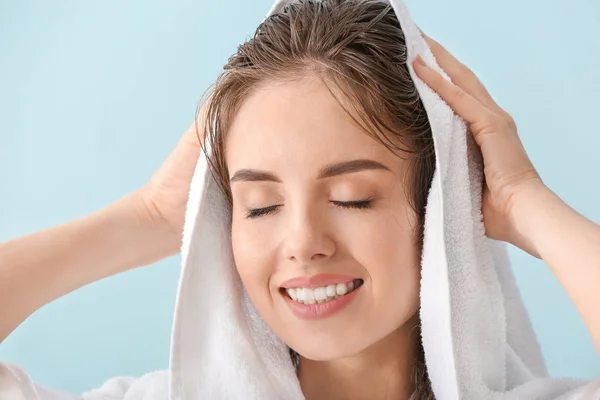 Hermosa mujer joven limpiando el cabello después de lavar contra el fondo de color —  Fotos de Stock