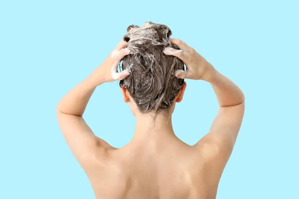 Mulher bonita lavando o cabelo contra fundo de cor, visão traseira — Fotografia de Stock