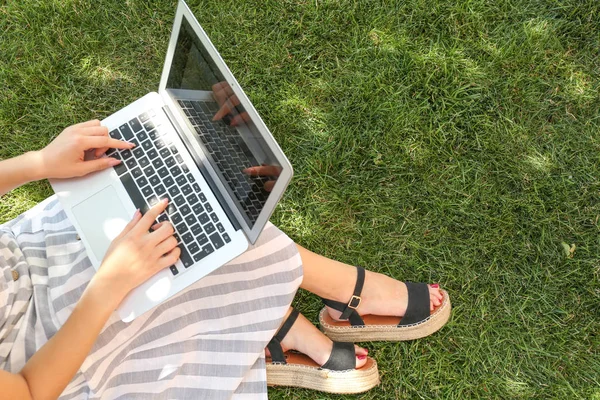 Blogueuse avec ordinateur portable assis sur l'herbe dans le parc — Photo