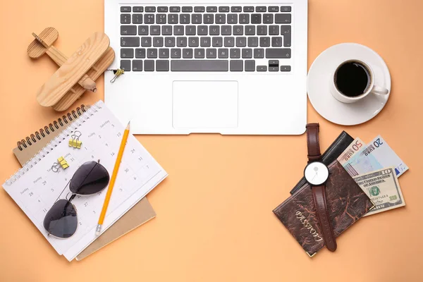 Laptop com calendário, passaporte, dinheiro e xícara de café no fundo de cor — Fotografia de Stock