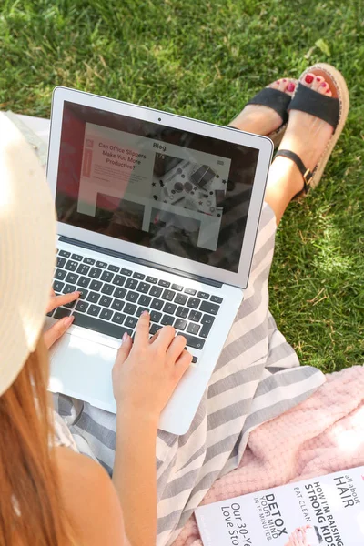 Blogger femenina con portátil sentado en la hierba en el parque —  Fotos de Stock