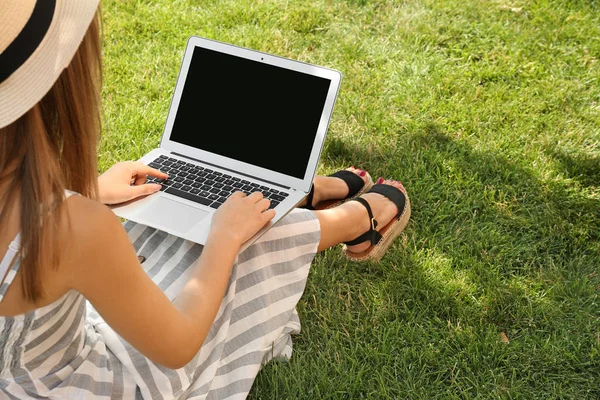 Blogueuse avec ordinateur portable assis sur l'herbe dans le parc — Photo