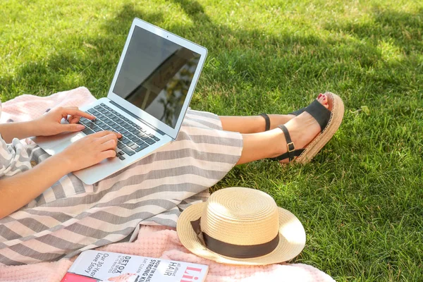 Blogueuse avec ordinateur portable assis sur l'herbe dans le parc — Photo
