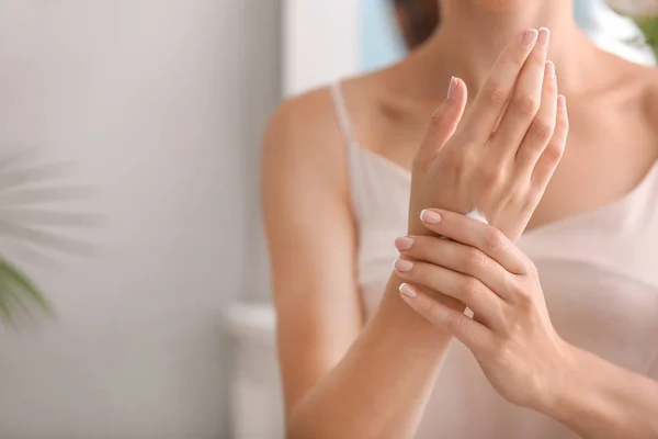 Young woman applying natural cream onto skin at home — Stock Photo, Image