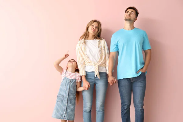 Портрет молодой семьи, глядя на что-то на цветном фоне — стоковое фото