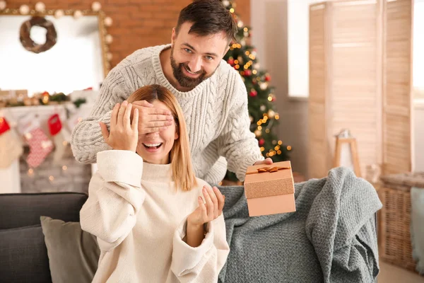 Happy man giving his wife Christmas present at home — Stock Photo, Image