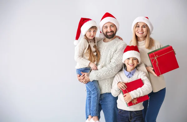 Happy family with Christmas gifts on light background — Stock Photo, Image