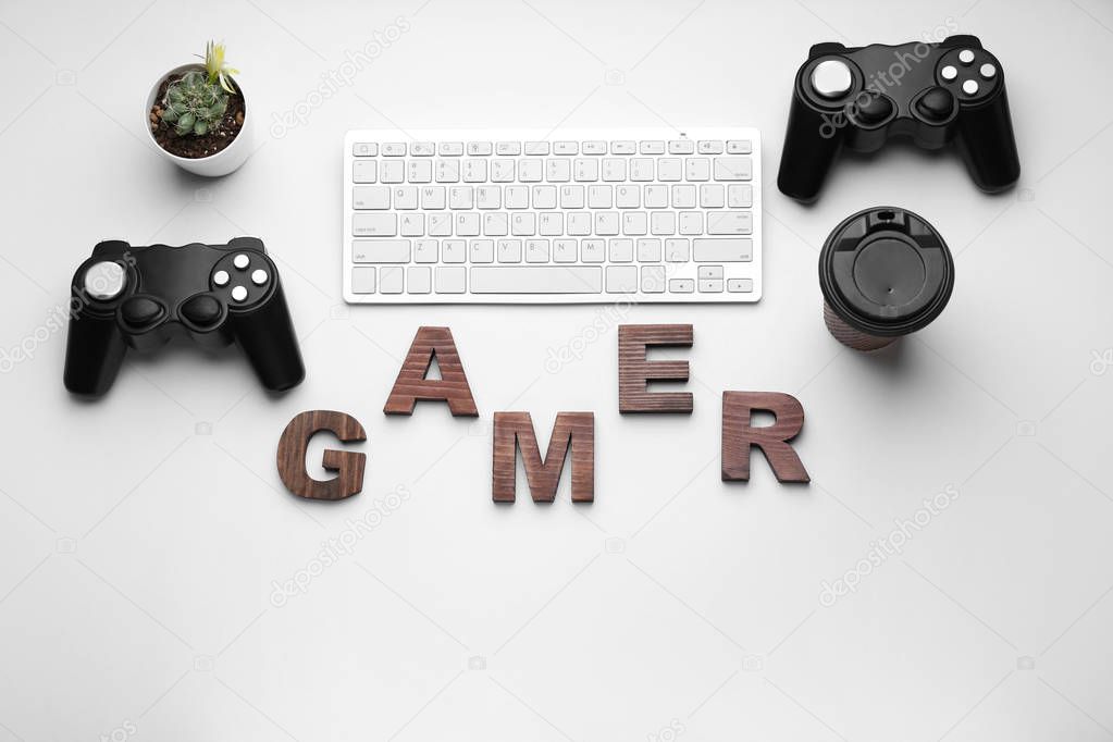 Computer keyboard with joypads, cup of coffee and word GAMER on white background