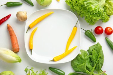 Beyaz arka planda farklı taze sebzeler ve tabak