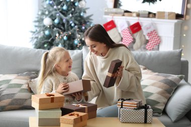 Evde Noel hediyeleri ile genç kadın ve onun sevimli küçük kızı