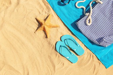 Kum plajda çanta ve havlu ile flip-flop