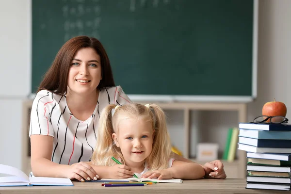 Profesor ayudando a niña a hacer la tarea en el aula —  Fotos de Stock