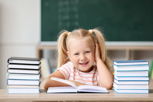 Carino piccola studentessa con molti libri in classe — Foto Stock