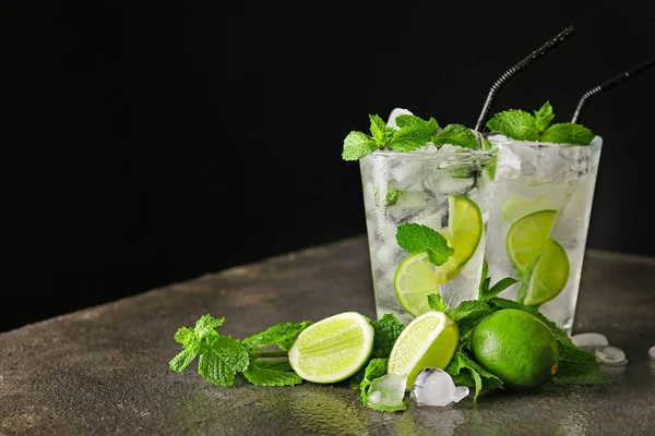 Glasses of fresh mojito on table against dark background — Stock Photo, Image