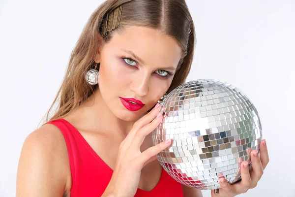 Fashionable young woman with disco ball on white background