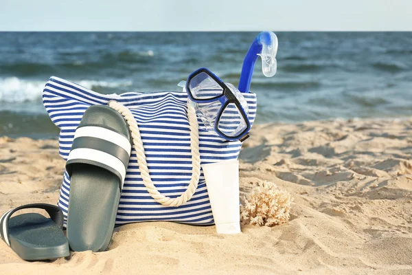 Bag with flip-flops, set or snorkeling and cosmetics on sand beach — Stock Photo, Image