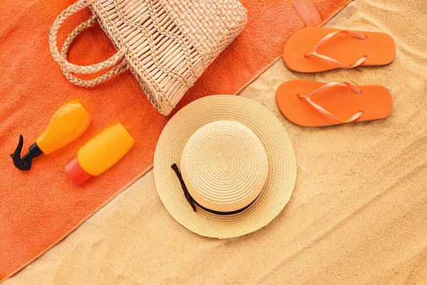 Flip-flops with bag, towel, hat and cosmetics on sand beach — Stock Photo, Image