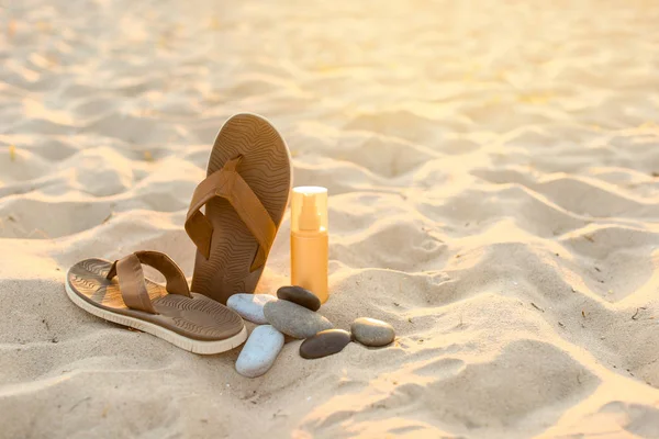 Chanclas con guijarros y cosméticos en la playa de arena — Foto de Stock