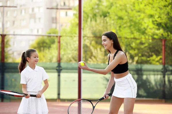 Küçük kız ve annesi kortta tenis oynuyorlar. — Stok fotoğraf