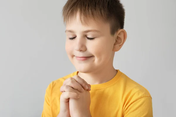 Praying little boy on light background — Stock Photo, Image
