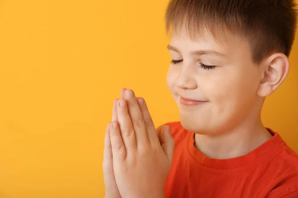 Praying little boy on color background — Stock Photo, Image