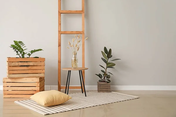 Mesa con cajas de madera y escalera cerca de pared de luz en la habitación — Foto de Stock