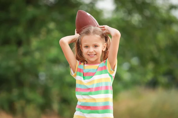 Porträt eines süßen kleinen Mädchens mit Rugby-Ball im Freien — Stockfoto