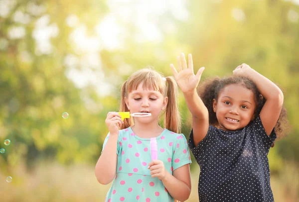 Cute little girls blowing soap bubbles outdoors — Stock Photo, Image