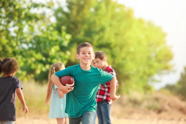 Cute little boy playing with rugby ball outdoors — Stock Photo, Image