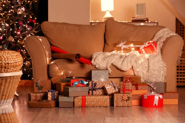 Veel mooie Kerstcadeaus in de buurt van een bank in de kamer — Stockfoto