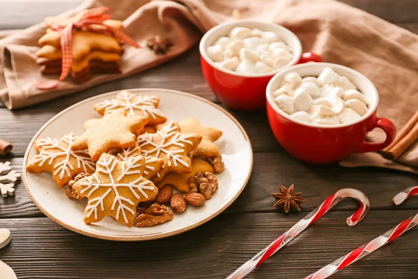 Plate with tasty Christmas cookies and cups of hot chocolate on wooden background — Stock Photo, Image