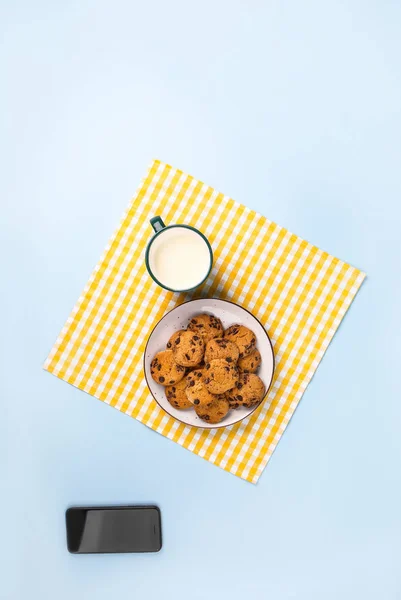 Placa com biscoitos saborosos, telefone celular e xícara de leite no fundo de cor — Fotografia de Stock