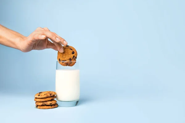 Mujer sumergiendo sabrosa galleta en vaso de leche sobre fondo de color —  Fotos de Stock