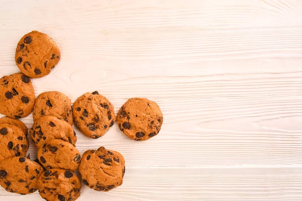 Gustosi biscotti con gocce di cioccolato su sfondo di legno chiaro — Foto Stock