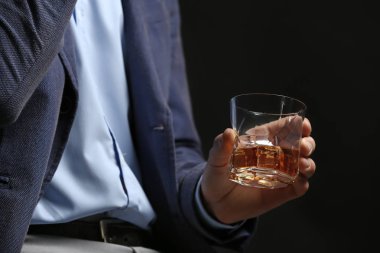 Koyu arka planda viski kadehi olan işadamı, yakın çekim