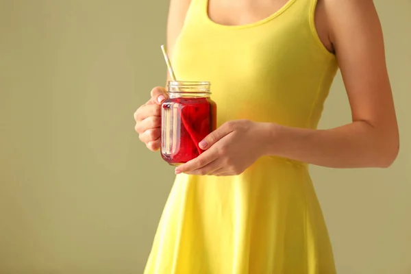 Woman holding mason jar of fresh pomegranate juice on color background — Stock Photo, Image