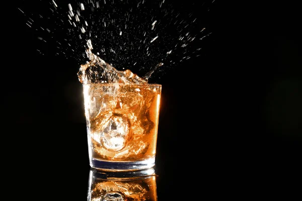 Spritzer Whisky im Glas auf dunklem Hintergrund — Stockfoto