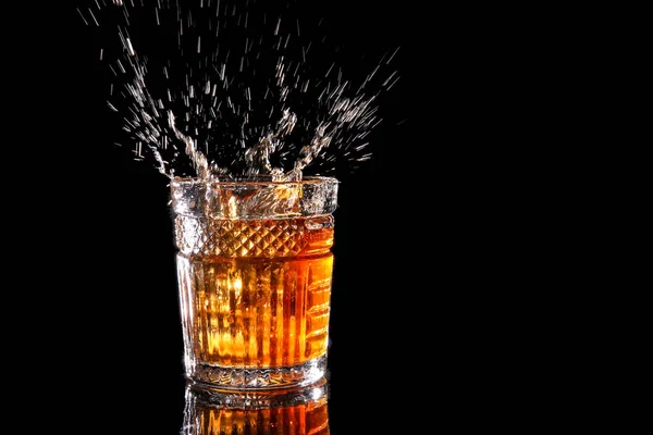 Splash whisky w szklance na ciemnym tle — Zdjęcie stockowe