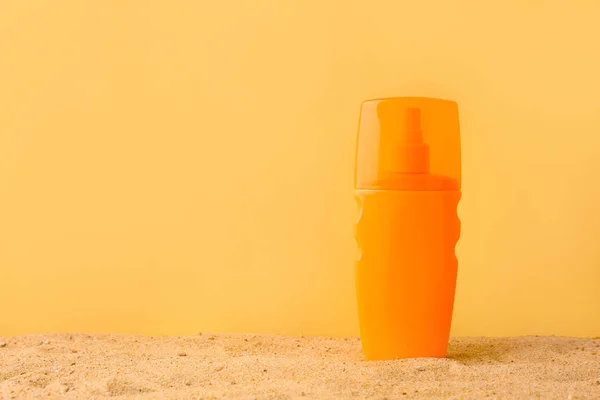 Botella de crema de protección solar sobre arena contra fondo de color — Foto de Stock