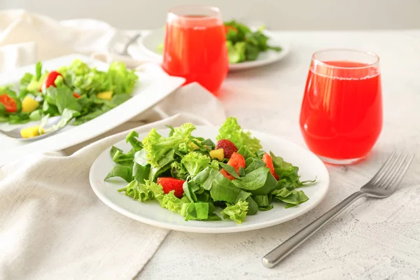 Placas com salada saborosa fresca e copos de suco na mesa — Fotografia de Stock