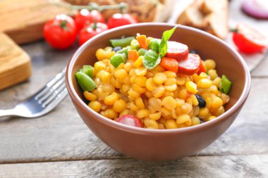 Ahşap masada lezzetli haşlanmış baklagiller, sebze ve sosis ile Kase