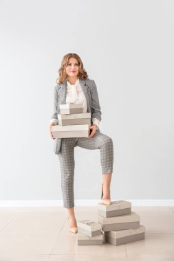 Işık duvara karşı hediye kutuları ile güzel genç iş kadını