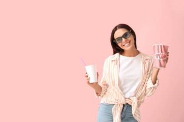 Patlamış mısır ve içki renkli arka planda film izlerken genç kadın