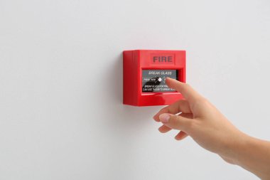 Woman using manual call point of fire alarm system clipart