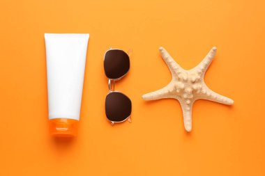 Güneş koruma kremi, güneş gözlüğü ve denizyıldızı renk arka plan üzerinde