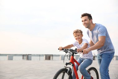 Baba oğluna dışarıda bisiklete binmeyi öğretiyor.